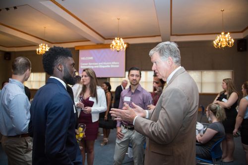Students and alumni chat at a networking event.