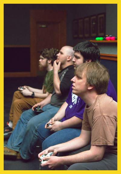 Gamers, mashing their controllers, intently watch the action off-screen.
